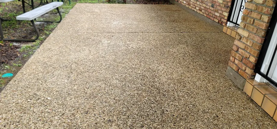 Freshly cleaned concrete driveway beside a brick home